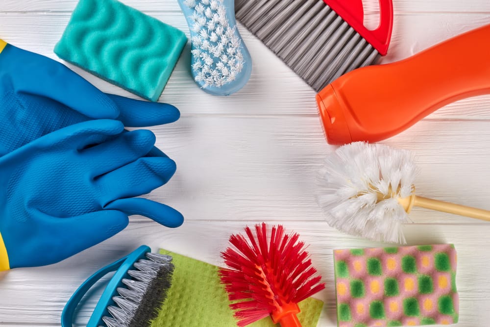 Assorted cleaning supplies including gloves, brushes, and sponges for professional cleaning services