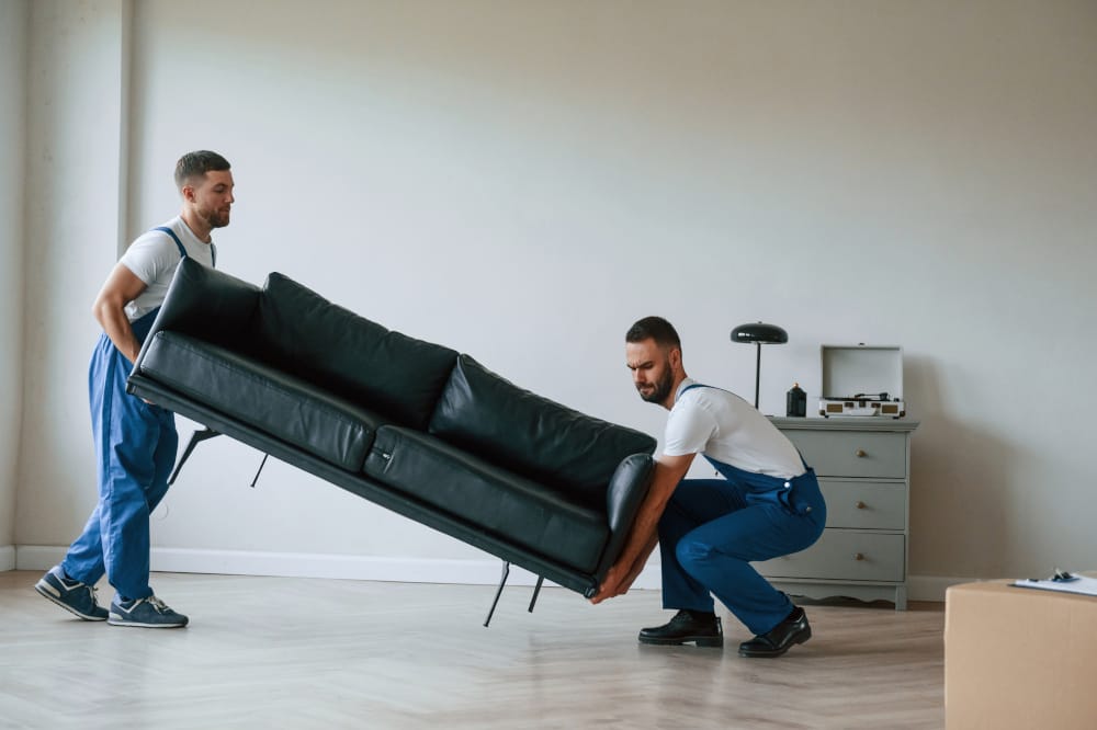 Professional movers lifting a black sofa during home and business removals service