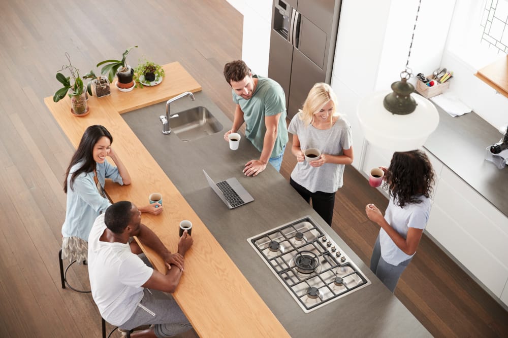 Group of people gathered around a kitchen island, enjoying coffee in a modern kitchen