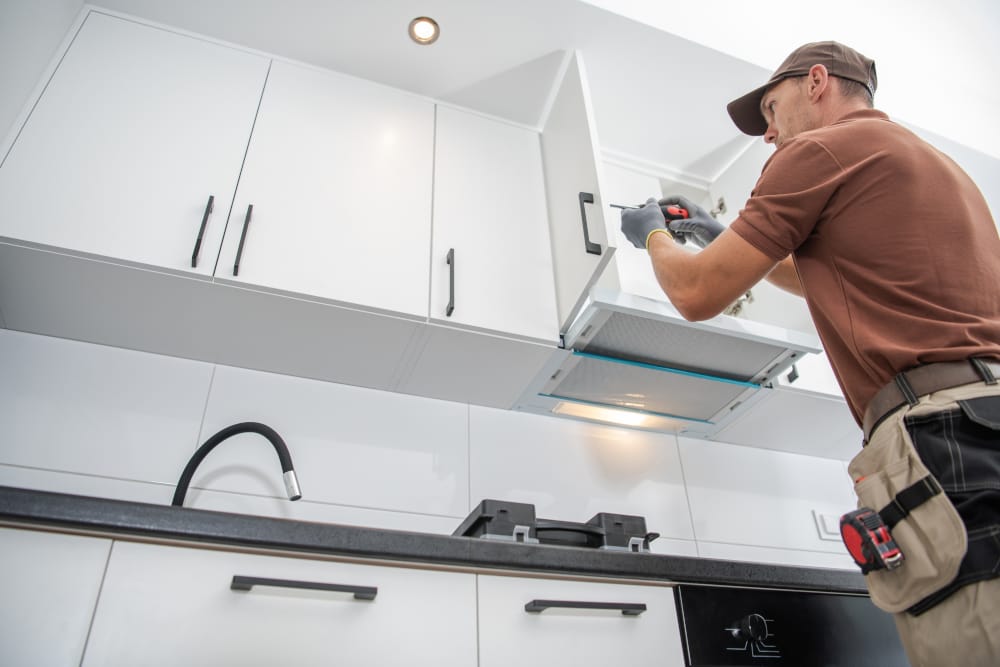 Professional installer working on a kitchen cabinet installation in a modern kitchen setup